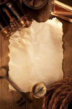 an old paper, compass, rope and other items are on a wooden table top