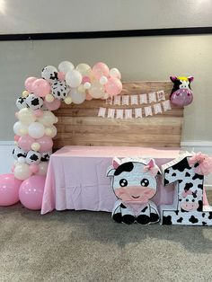 a cow themed birthday party with balloon decorations and pink table cloths on the floor