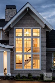 a house that is lit up at night with the lights on and windows open to let in light