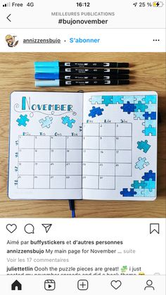 an open planner with blue puzzles on it and two pens next to the page