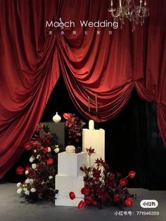 red and white flowers are on display in front of a stage curtain with chandelier