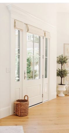 a white room with two doors and a basket on the floor