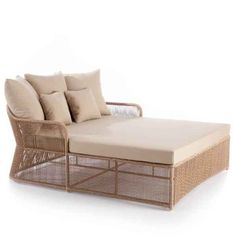 a wicker daybed with beige cushions and pillows