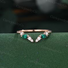 an emerald and diamond ring sitting on top of a green surface