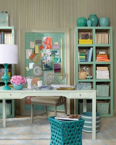 a desk with a lamp, bookshelf and pictures on the wall