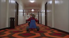 a little boy riding a toy car down a hallway