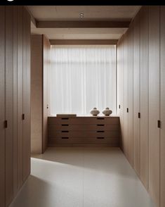 an empty room with two vases on the counter and wooden cabinets in front of it