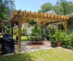 an outdoor patio area with potted plants and flowers on the pergolated roof