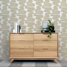 a wooden dresser sitting in front of a wall with a plant on top of it