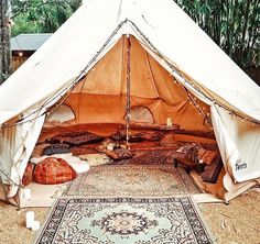 a large tent is set up in the middle of a field with pillows and rugs