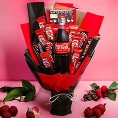 a bouquet of chocolates, candy bars and strawberries on a pink background with berries