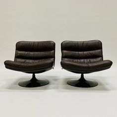 two brown leather chairs sitting next to each other on top of a white flooring