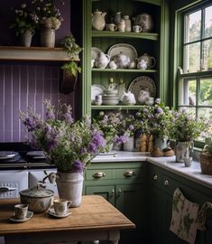 a kitchen filled with lots of green cabinets and purple flowers in vases on the counter