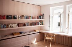 an empty room with bookshelves and a chair next to the window in front of it