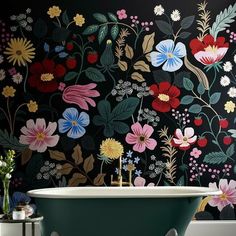 a bath tub sitting next to a wall with flowers painted on the side of it