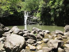 there is a small waterfall in the middle of some rocks and water with trees around it