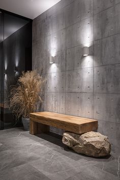 a wooden bench sitting in front of a wall with lights on it and a plant next to it