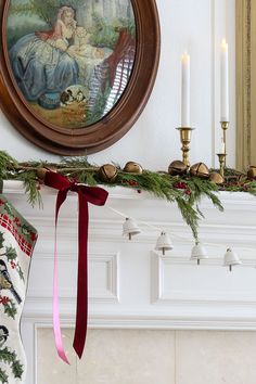 a christmas mantle with stockings, candles and a painting on the mantel above it