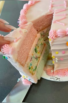 a person is holding a knife to cut a cake with white frosting and sprinkles