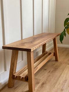 a wooden bench sitting on top of a hard wood floor next to a potted plant