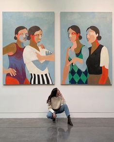 a woman sitting on the ground in front of two paintings