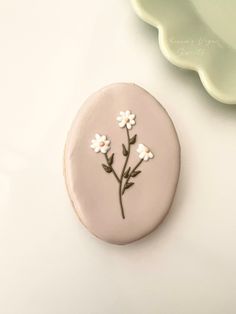 a cookie decorated with white flowers on top of a table next to a green plate