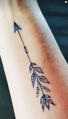 a woman's arm with an arrow tattoo on it