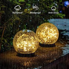 two lights that are sitting on top of a wooden table with rain falling over them