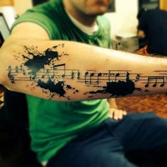 a man with a tattoo on his arm that has music notes painted on the side