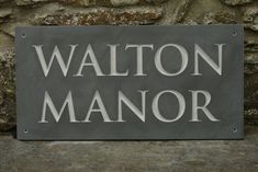 a sign that is on the side of a stone wall saying walton manor, with white lettering