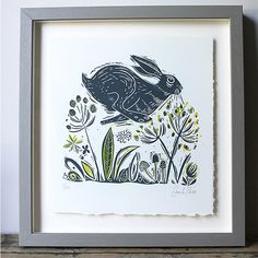 a drawing of a rabbit in the grass with flowers and plants on it's side