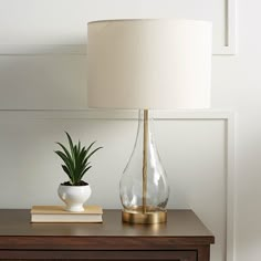 a table with a lamp and a vase on it next to a bookshelf