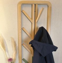 a coat rack with clothes hanging on it next to a flower and a vase filled with flowers