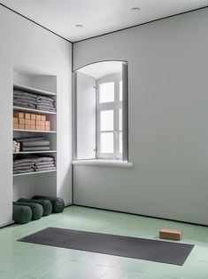 a yoga mat is on the floor in front of an empty room with shelves and windows