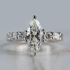 a close up view of a ring with a pear shaped diamond in the center and side stones