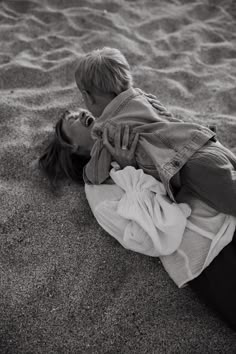 a man and woman laying on top of a sandy beach