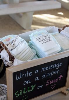 several diapers are in a basket on the floor next to a sign that says write a message on a diaper silly or sweet