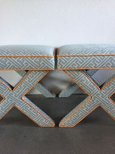 an upholstered bench with orange trim on the edges and two matching footstools