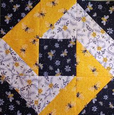 a yellow and black patchwork quilt with bees on the top, flowers in the middle