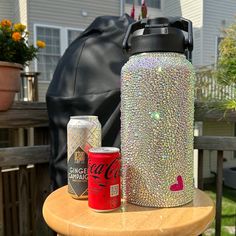 a bottle and can sitting on top of a wooden table next to a black bag