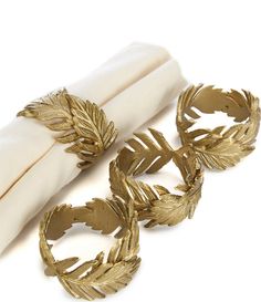 three gold leaf napkin rings sitting next to each other