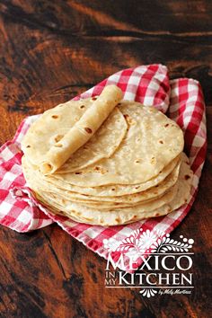 stack of flour tortillas on red and white checkered napkin