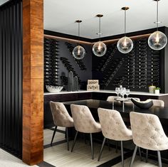 a dining room table and chairs with wine bottles on the wall behind it in front of a bar