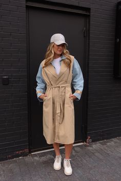 DETAILS: Introducing our stylish Paige Khaki Combo Trench Coat, a unique statement piece for the colder days ahead! This maxi-length coat features an innovative design with a denim jacket base layered underneath a sleeveless khaki trench coat, creating a distinctive and eye-catching look. The khaki details on the denim long sleeve cuffs add an extra touch of flair. With two rows of buttons and a wrap-around tie closure, this coat offers versatility in styling and fit. Crafted from a lightweight, Chic Oversized Cotton Outerwear, Winter Denim Long Coat, Trendy Long Cotton Coat, Fall Utility Outerwear For Day Out, Chic Cotton Outerwear For Layering, Chic Cotton Outerwear, Chic Long Cotton Coat, Utility Long Coat For Work, Chic Oversized Gabardine Outerwear