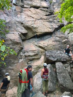 three people climbing up the side of a rock face with ropes attached to them and roped together