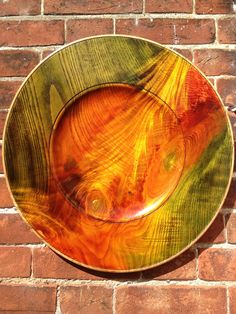 an orange and yellow bowl sitting on top of a brick wall next to a brick wall