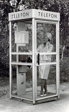 a woman is standing in a phone booth