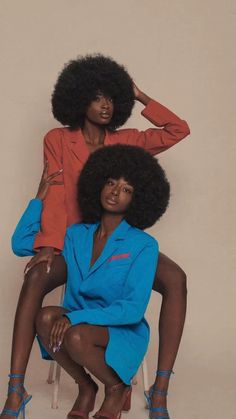 two women sitting on top of each other in front of a white background, one with an afro