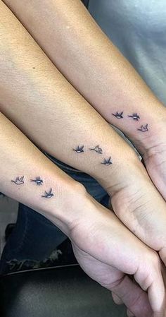 two people holding hands with small birds on them