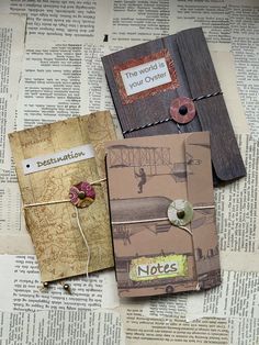 three small notebooks sitting on top of an old book covered in paper and string